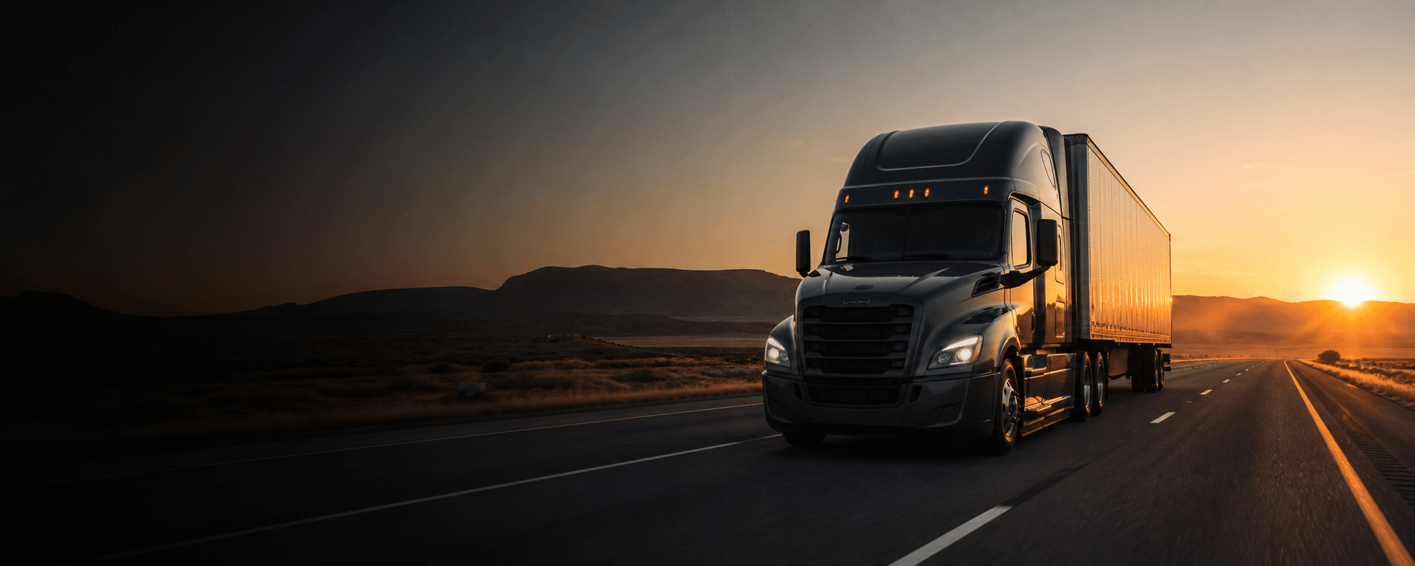 A professional semi truck traveling on an open highway at sunrise